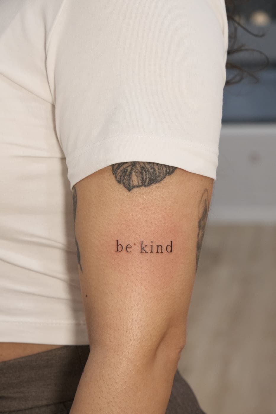 Frase «be kind» no braço