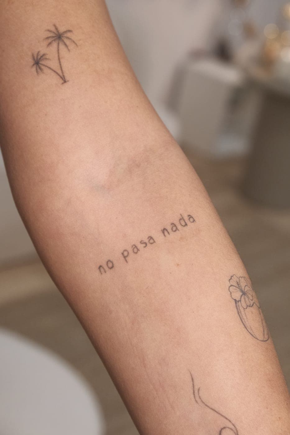 Frase «no pasa nada» e pequenos desenhos no antebraço
